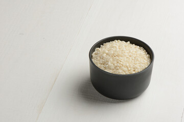Arroz redondo en un bol de cocina negro en la mesa blanca