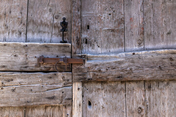 old wooden door with steel locking lever in a small isolated village in the French Alps