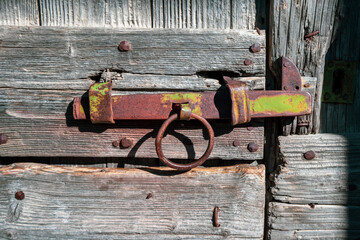 old wooden door with steel locking lever in a small isolated village in the French Alps
