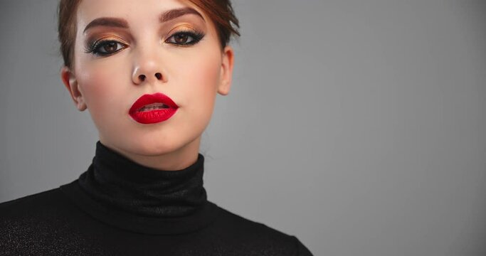 Beautiful woman with bright professional makeup. Closeup cinematic footage of an sexy girl with a red lipstick on lips. Model with a fashion brown eye make-up. SLOW MOTION. BMPCC4K. 12 bit ProRes.
