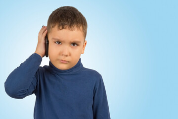 A six-year-old Asian boy with a serious expression uses a mobile phone to talk. The image has a blank space for your text.