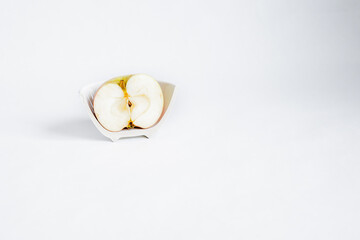 Sliced ​​half of an apple in a broken half of a ceramic small plate on a white background. Place for text. Concept.