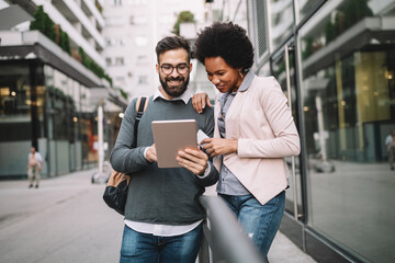 Cheerful people having fun, talking with electronic tablet in city outdoor