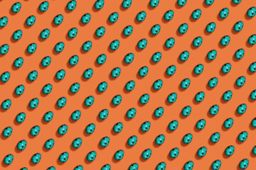 Pattern of colored Easter eggs in green on an orange background. Minimal easter concept. Easter spring holiday background.