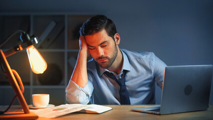 sleepy man with closed eyes working late in office