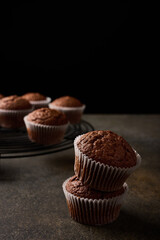 Homemade chocolate cupcakes in baking paper forms on wooden background, selective focus, close up, vertical orientation