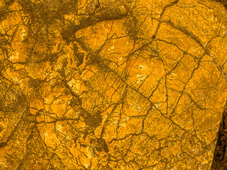 Gold texture rough leaf foil with cracks background. Shiny yellow abstract textured golden stone