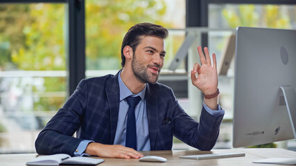 happy businessman showing okay sign and having video call in office