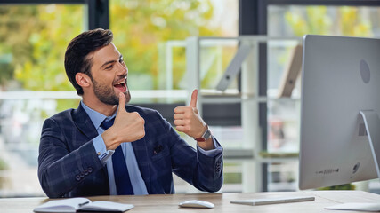 happy businessman showing thumbs up and having video call in office