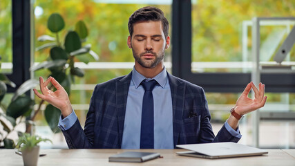 businessman with closed eyes meditating in office