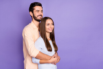 Photo of happy young married couple stand look dream empty space hug isolated on purple color background