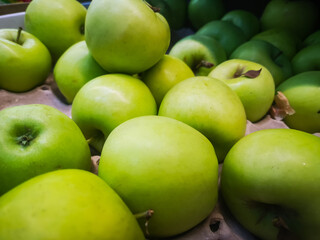ripe green apples in a box for sale in a supermarket