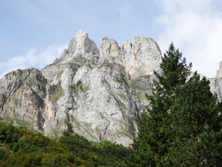 Fototapeta na wymiar Picos rocosos vistos desde un ángulo bajo y enmarcados por árboles en las inmediaciones del Parque Nacional de los Picos de Europa, España