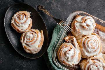 Cinnamon sinnabon bun, with vanilla fudge on a dark background.