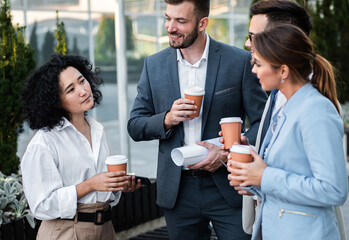 Coworkers standing outside in front of office buildings discuss about business plan.