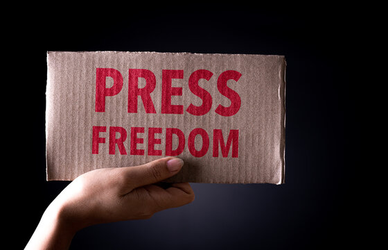 World press freedom day concept. Hand  holding cardboard paper with the text on dark background, conceptual image, symbol of press or speech freedom.