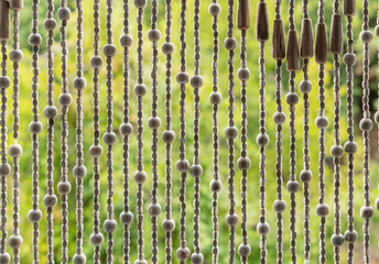 Detail of a wooden hanging curtain on natural green background  - 421013203