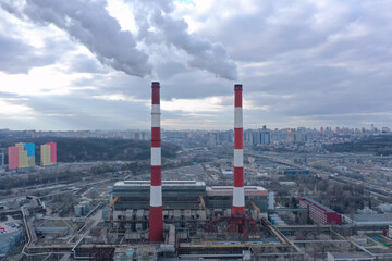 Pipes with white smoke. Pipes of a city gas boiler room with white smoke against a sky. Top view from a drone.