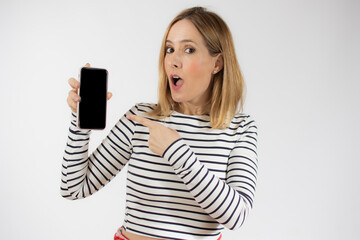 Naklejka premium Portrait of a smiling young woman showing blank screen mobile phone while standing isolated over white background