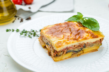 Eggplant moussaka Greek cuisine on white plate on white concrete table