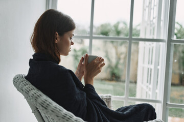 Woman with a hot mug in hand near the window