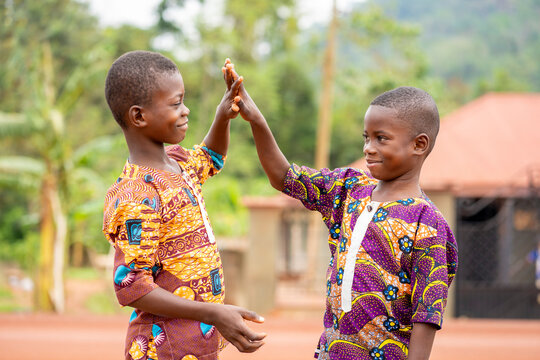 image of two africa kids- cheerful black boys shaking hands outdoor