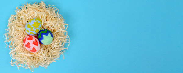 Colorful traditional hand painted Easter eggs in the nest isolated on a blue background.