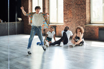 Happy handsome guy improvising movements before friends
