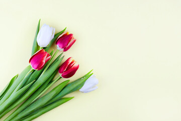 Bouquet of tulips on a yellow background. Greeting card. Flat lay, top view. Copy space for text.