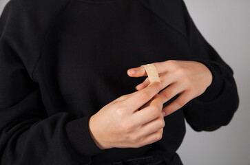 Caucasian woman putting adhesive bandage on her finger.