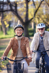 Cheerful active senior couple with bicycle in public park together having fun. Perfect activities...