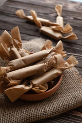 Top view of handmade caramels wrapped in wax papers on dark board.