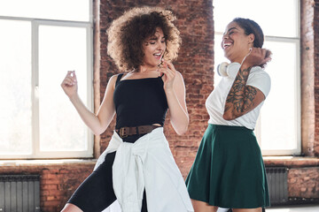 Obraz premium Merry pretty ladies dancing hip-hop in studio