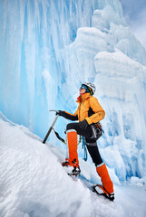Woman climbing frozen waterfall in the mountains