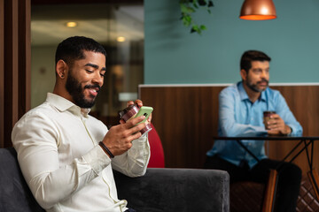 black business man looking at cell phone screen on sofa of business lounge. .