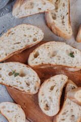 Sliced fresh baked ciabatta bread on kitchen towel over grey texture background.