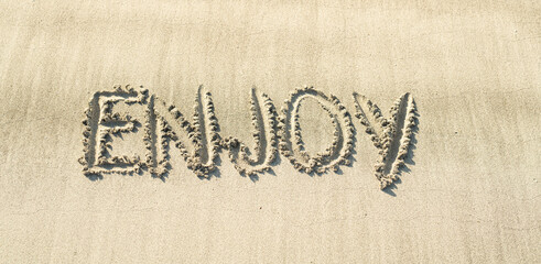 Enjoy genießen handschriftlich in den Sand geschrieben am Strand