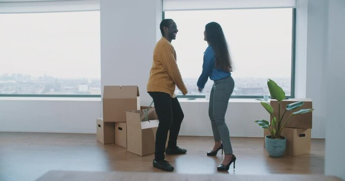 Happy multiethnic couple dancing in the livingroom in their new flat