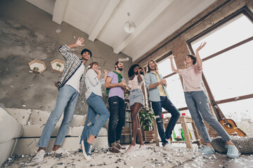 Full size low angle view photo of positive men and women fly confetti party mood indoors inside...
