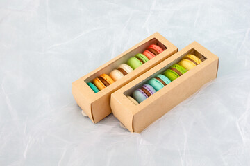 Multicolored macarons in a paper box and multicolored sweets on a romantic background.