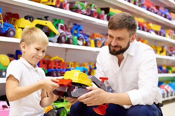 A little boy with his father is choosing toys in a children's store.