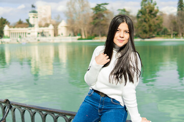 Young girl in blue jeans and white sweater with lake background