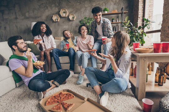 Portrait of attractive cheerful friends having fun eating junk snack communicating gathering in house loft brick style interior indoors