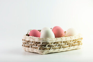 Pink, White easter eggs in wooden basket on white background.