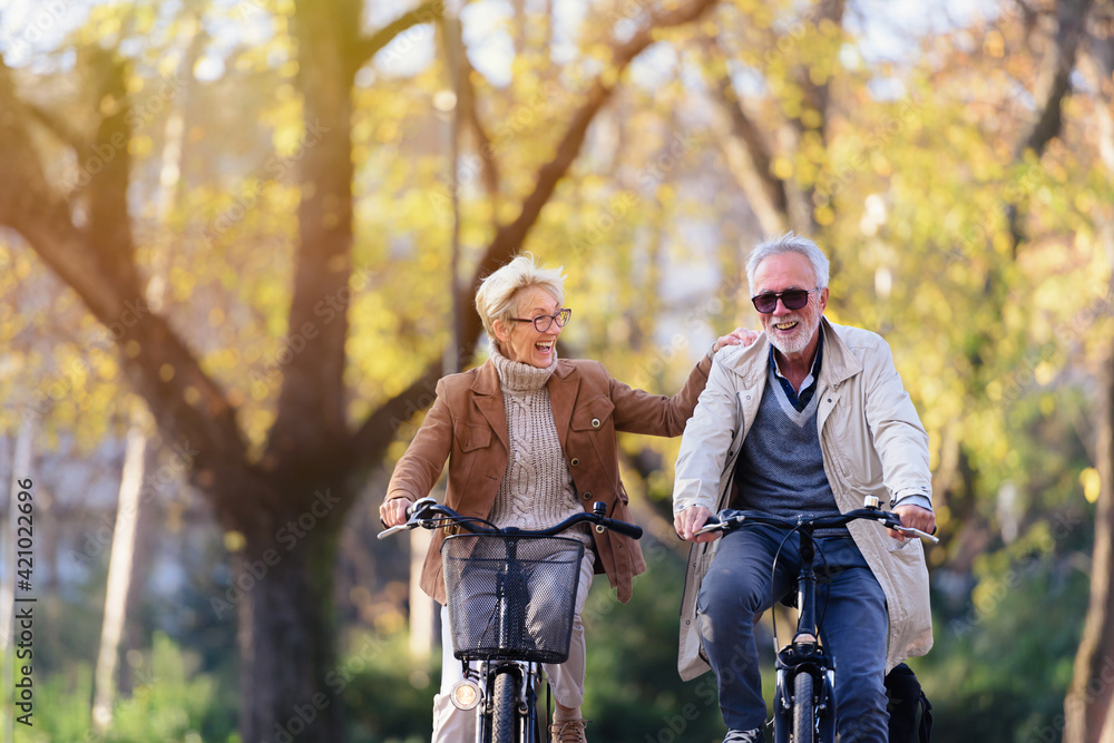 Wall mural cheerful active senior couple with bicycle in public park together having fun. perfect activities fo