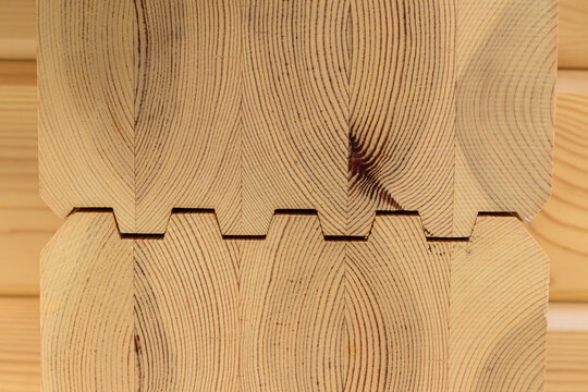 Glued timber beams. Zigzag seam. Pattern of parallel brown woody stripes.