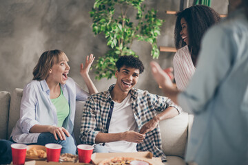 Portrait of attractive cheerful friends sitting on sofa having fun talking discussing news good mood in house loft style indoors