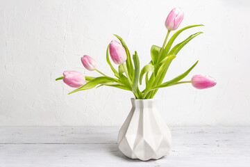 Bouquet of gentle pink tulips in ceramic vase on white background