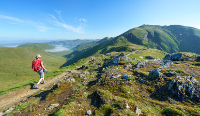 A female hiker and their dog walking, hiking along a mountain path towards the summit of Ben Lawers...