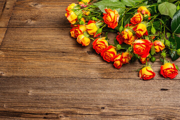 Bouquet of bright yellow-orange roses on old wooden table